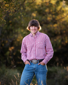 A high school senior boy standing in western attire for his portraits. 