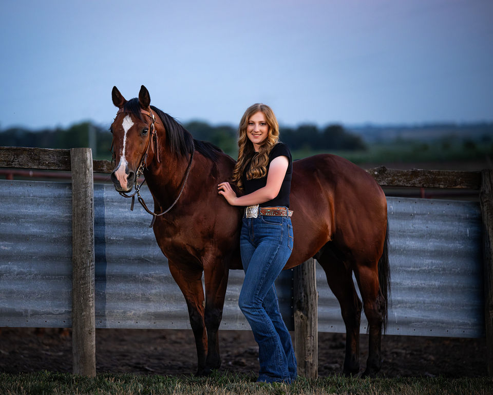 Senior cowgirl leans over her bay quarter horse gelding.