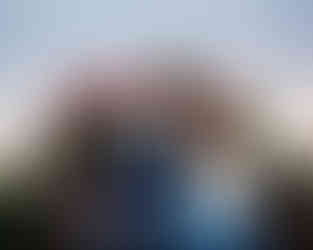 Older siblings sitting on the set of rustic winter pickup sessions pointing playfully at each other. 