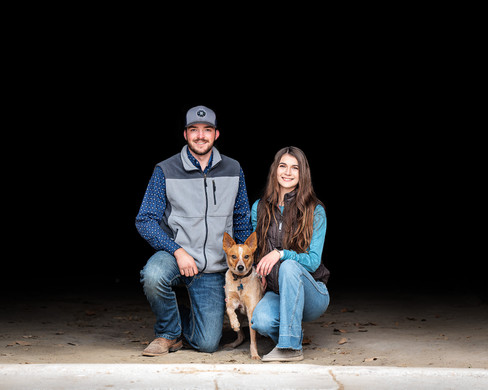 Couple standing in barn door entry with family dog 