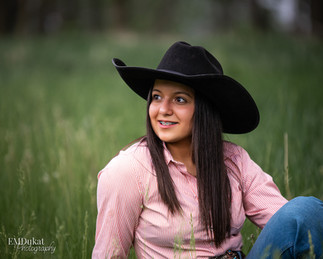 Cowgirl sits in the grassy field.