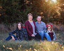 Family sitting on vintage red couch in field for our rustic winter pickup sessions