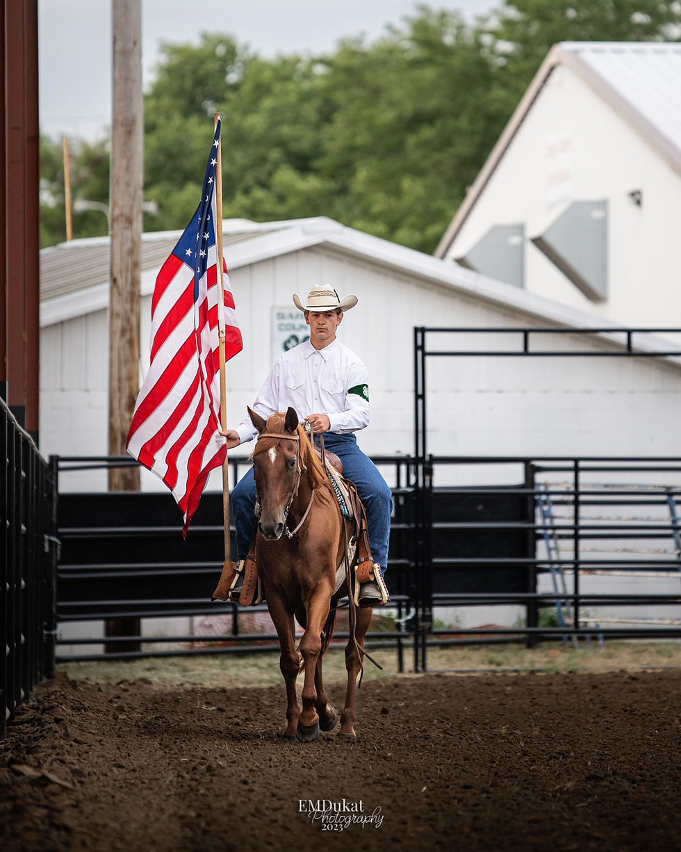 4-H cowboy carries the American flag while the anthem plays