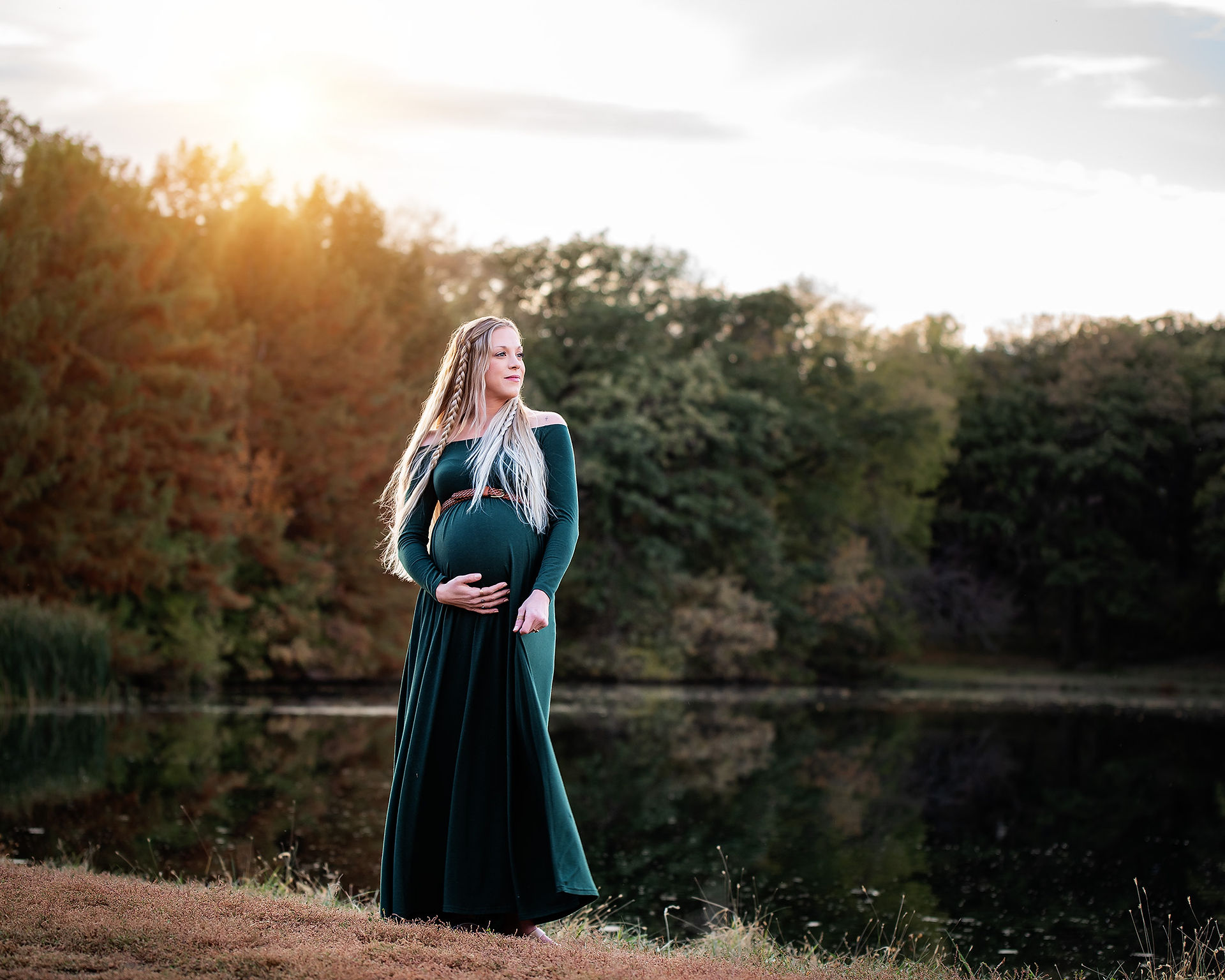 Woman in maternity dress by a lake at sunset 