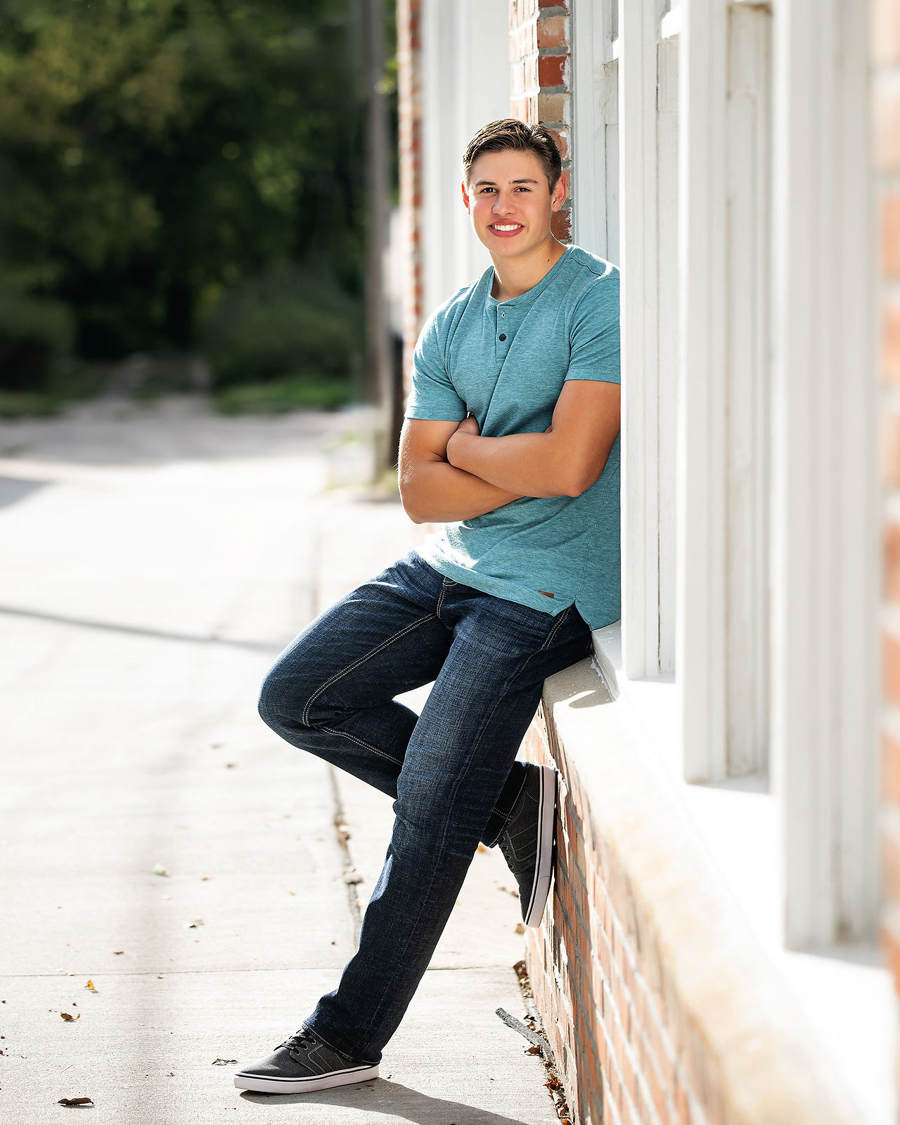 Boy in light blue t-shirt leaning against brick wall on a street walkway in Gretna, Nebraska during an autumn afternoon.