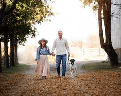 Couple walking down drive with dog in autumn