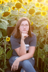 teen sitting in Nelson Produce sunflower field in Valley, Nebraska
