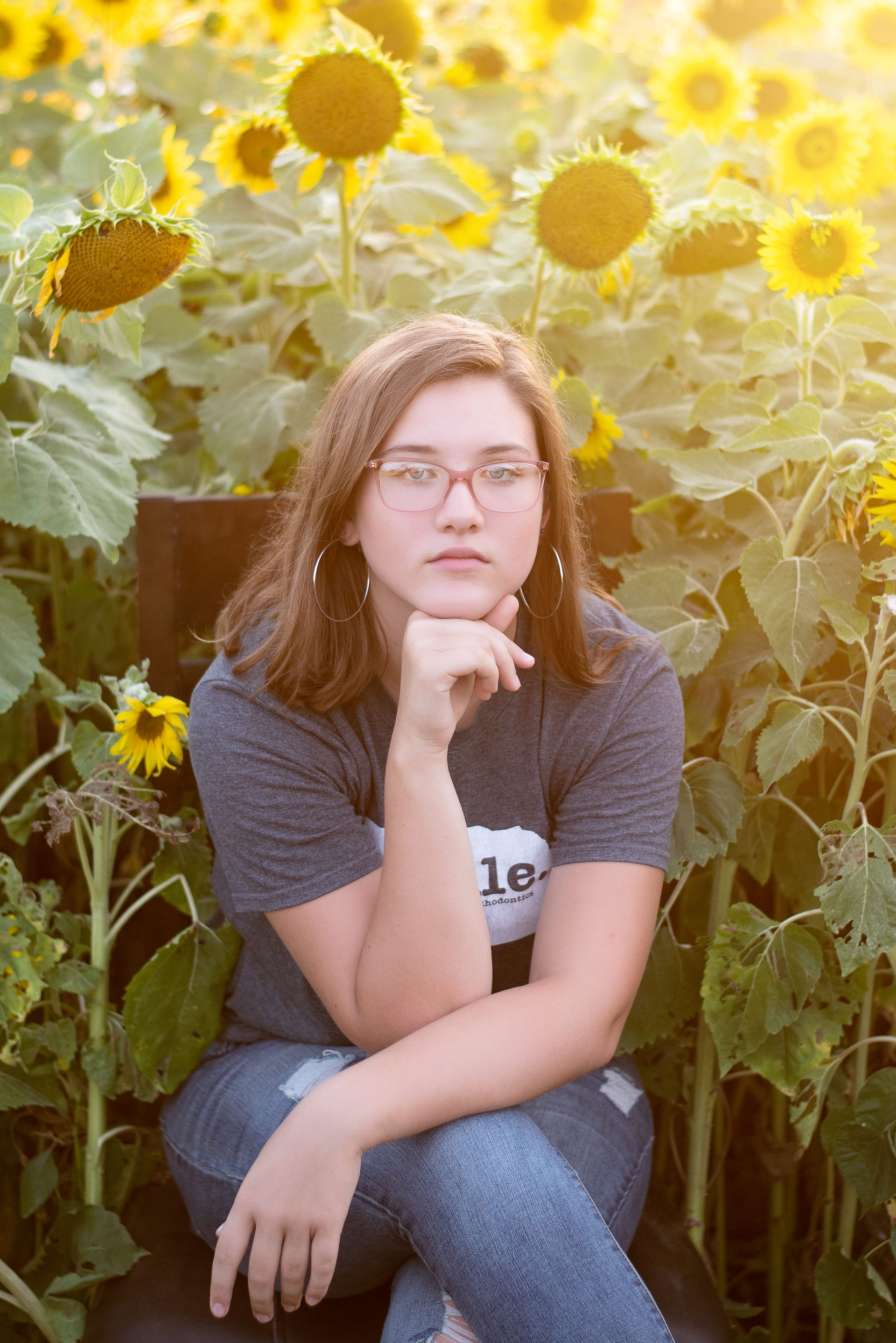 teen sitting in Nelson Produce sunflower field in Valley, Nebraska