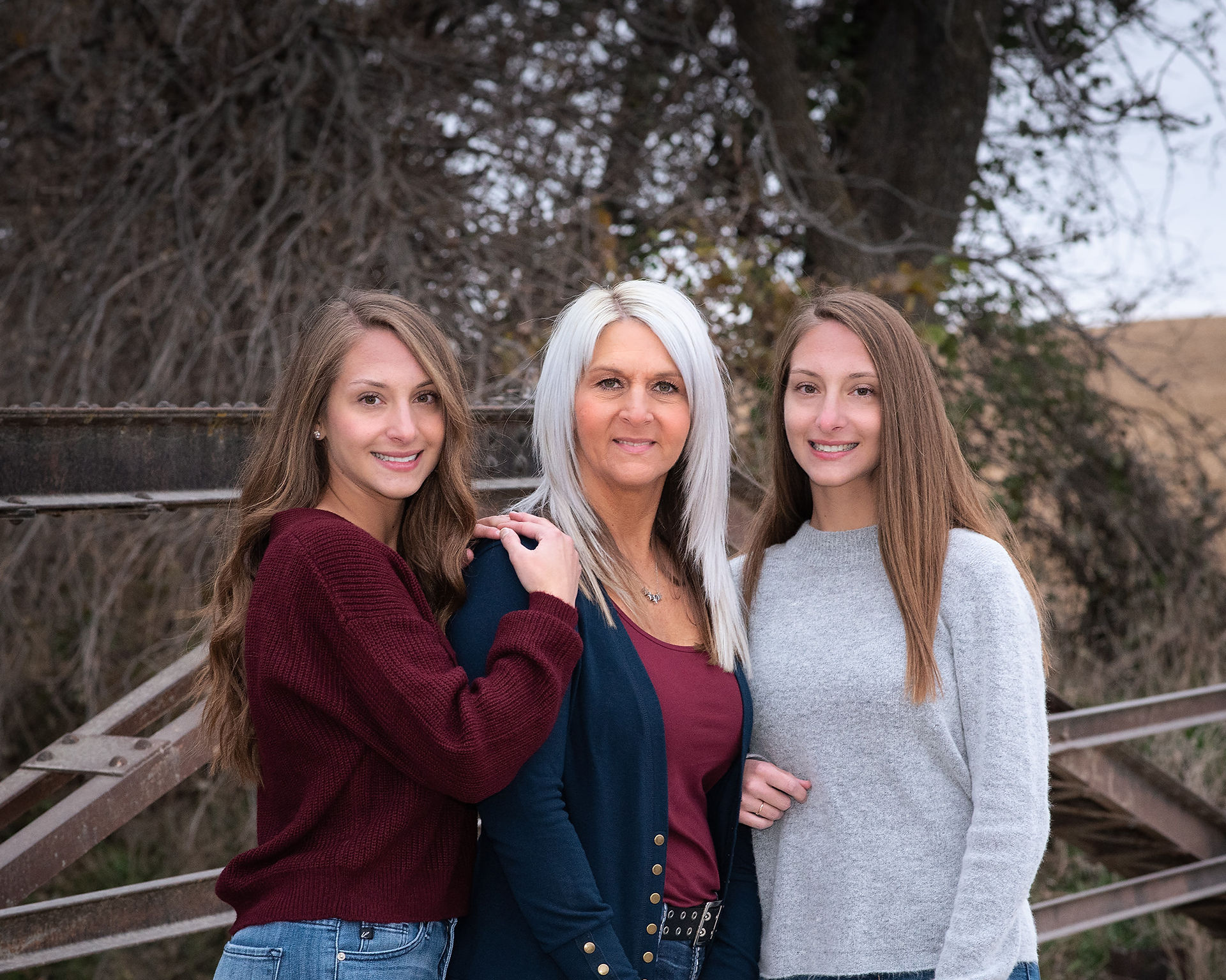 Mom and her girls pose for a mother daughter photo on rustic bridge