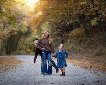 Two young children with their older sister, being goofy on a dirt road. 