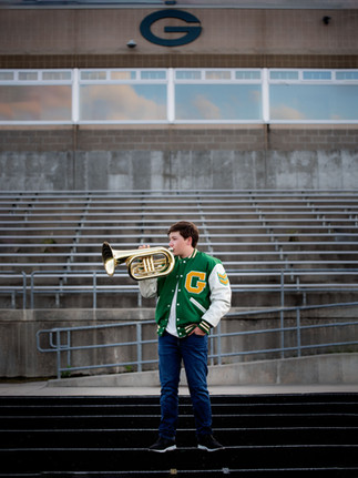 senior boy on football field playin his marching baritone at Gretna High School