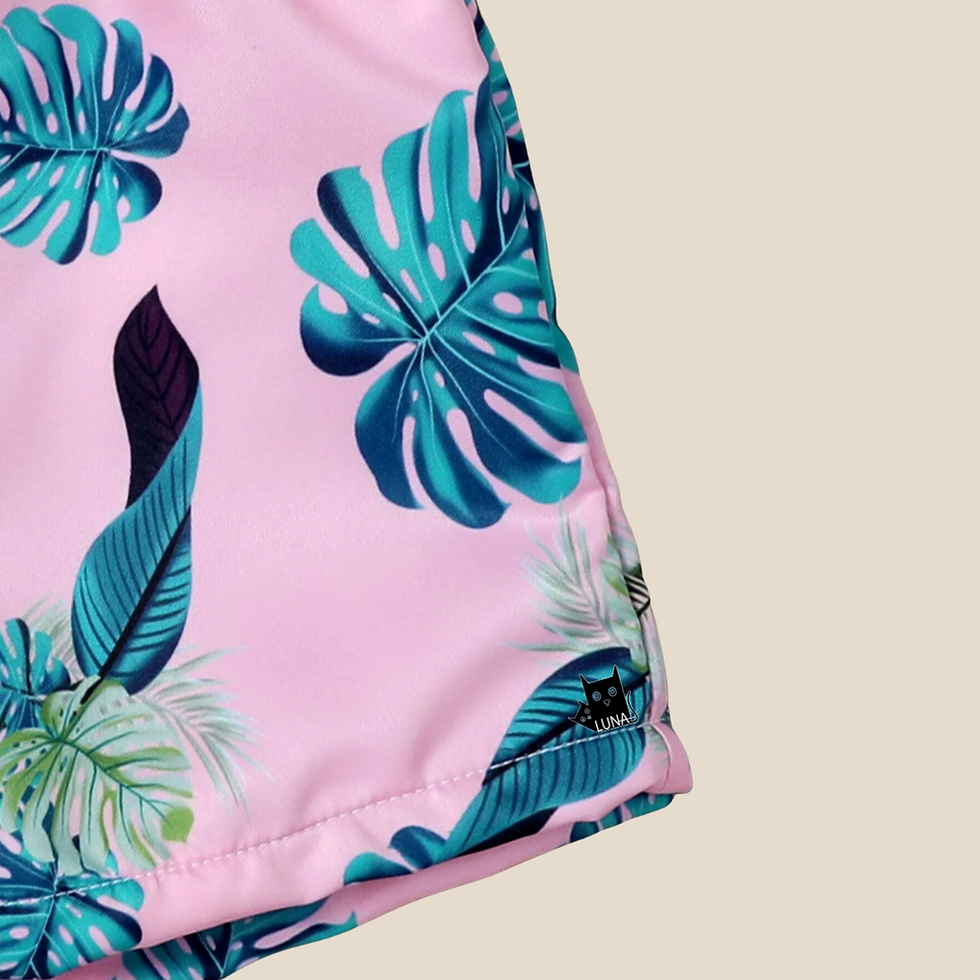 Thumbnail: pink swimming trunks for toddler with green leaves around side view in beige background