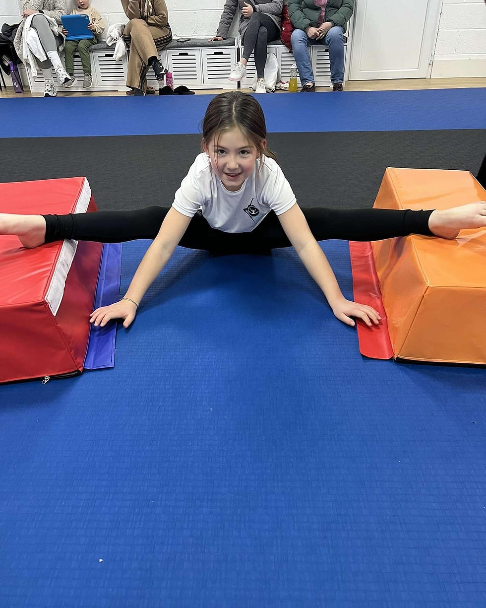 Eye-level view of a toddler practicing basic gymnastics moves on a soft mat in a bright studio