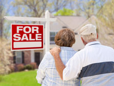 Downsizing older couple stood in front of their family home