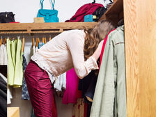Woman with her head buried in a cluttered wardrobe