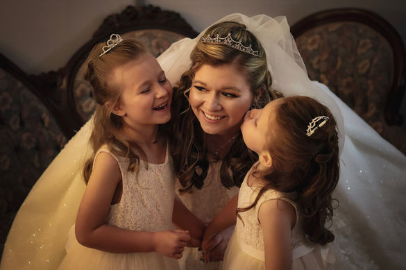 bride being kissed on the cheek by flower girls
