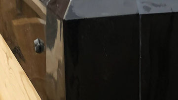 Close up detail of a gloss black capping piece fitted onto a timber fence post
