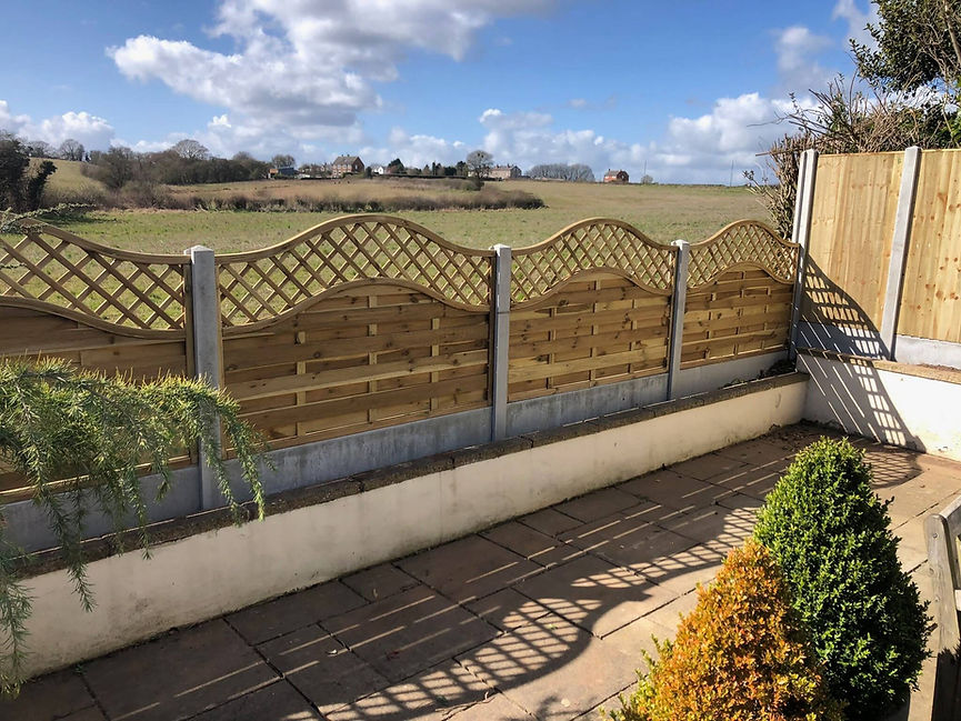 Decorative wave top timber fence panels installed on a concrete gravel board base