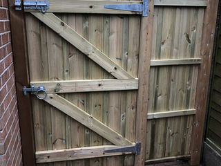 Weathered double wooden driveway gates with heavy black iron hinges