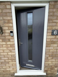 A close-up of a modern front door with a long, vertical glass pane