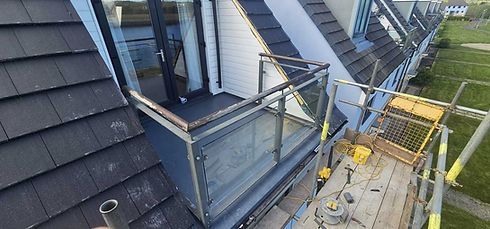 Flat roof balcony construction with modern glass balustrade installation