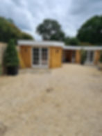 Timber garden buildings with French doors and gravel courtyard.