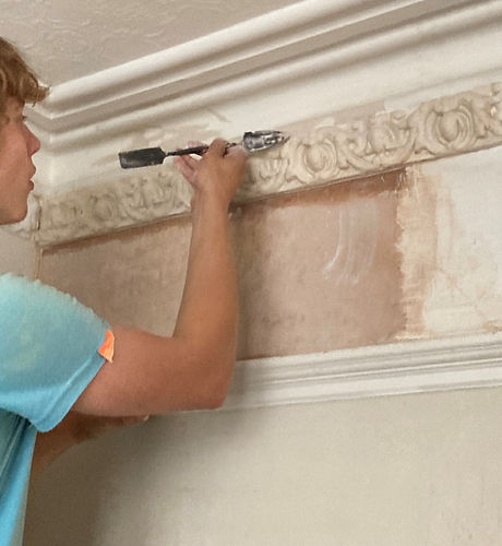 Plasterer repairing cornice moulding