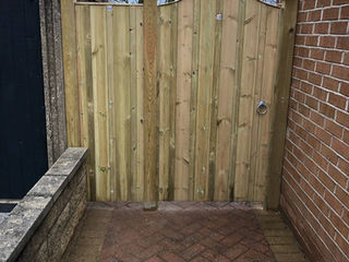 Section of tall wooden fencing and a matching side gate in a garden