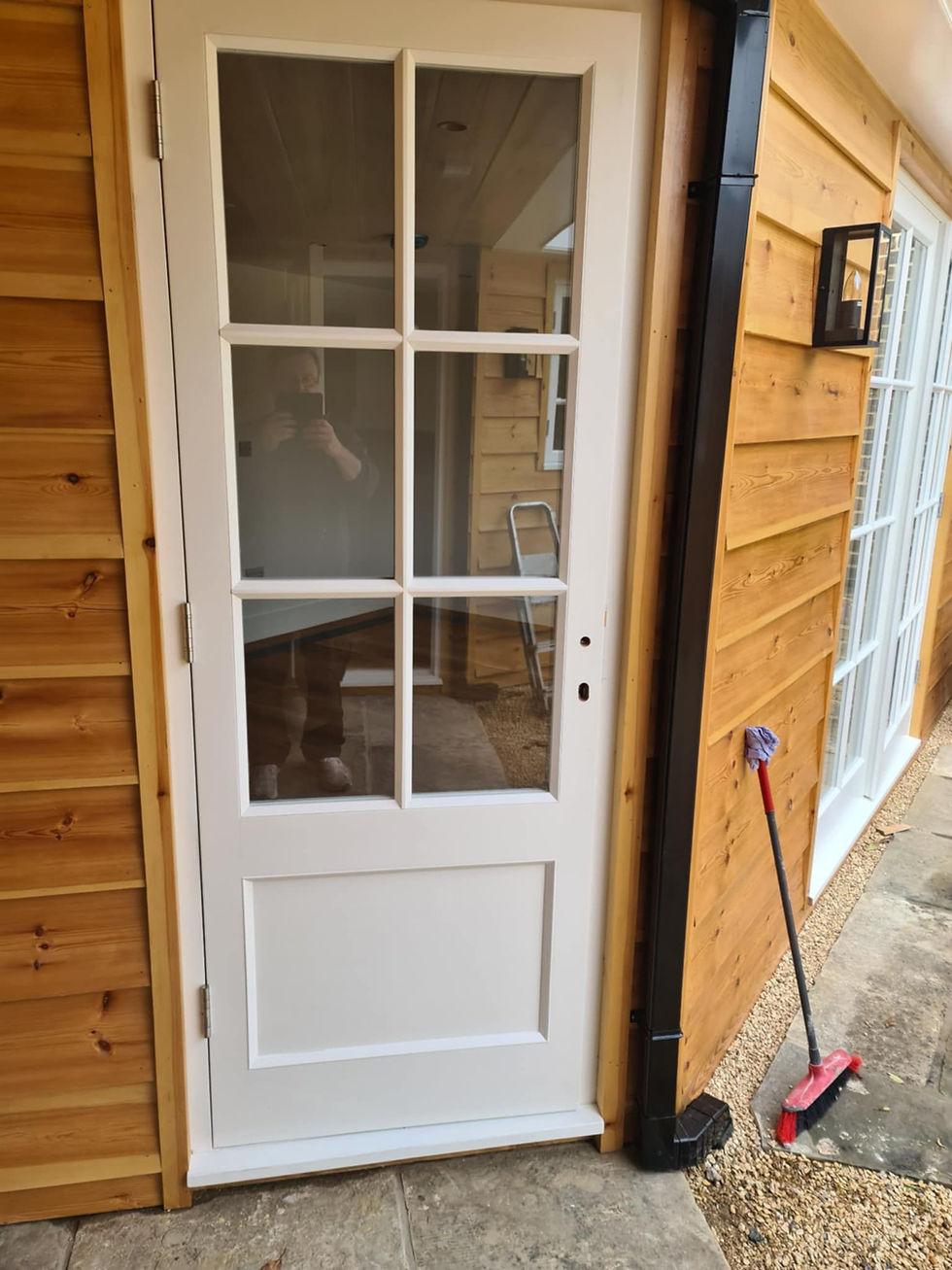 White glazed door installed in a timber garden building.