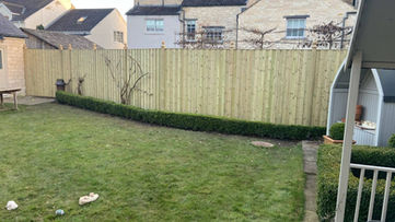 Tall vertical board timber privacy fence enclosing a spacious green garden lawn