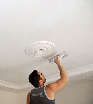 Man using a plastering trowel to smoothen plaster on the ceiling