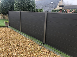 Dark grey composite decking area matching an adjacent privacy fence
