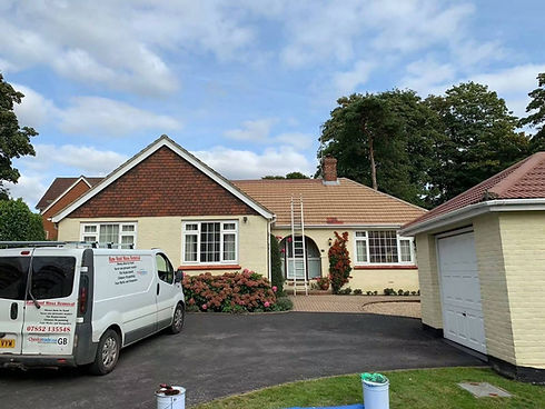 White roofing company van parked on a driveway in front of a bungalow house with red tile roof