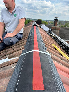 Roofer sitting by a newly replaced roof ridge