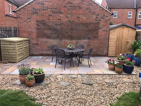Paved garden patio with a central dining set and decorative gravel borders