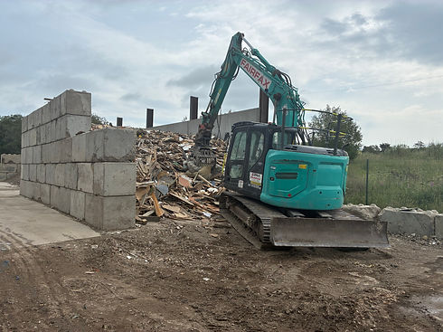 Excavatore moving waste to brick enclosure