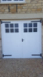 White garage double doors with black hinges and handles.