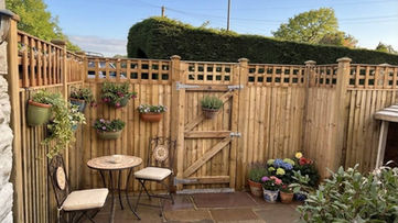 Cosy paved patio corner with a matching table and chairs set against trellis topped timber fencing