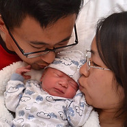 Asian parents kissing newborn