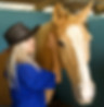 Woman in a stable hugging a horse.
