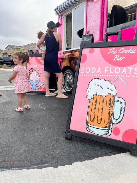 A customer browsing the menu in front of The Cookie Bar’s “Cutie 2” truck, with a large sign displaying their menu offerings in Las Vegas, Nevada.