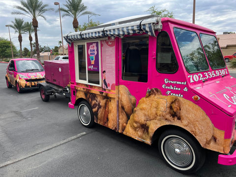 The Cookie Bar’s vibrant pink “Cutie 2” soft serve truck parked outdoors, featuring detailed images of soft serve cones on its exterior.