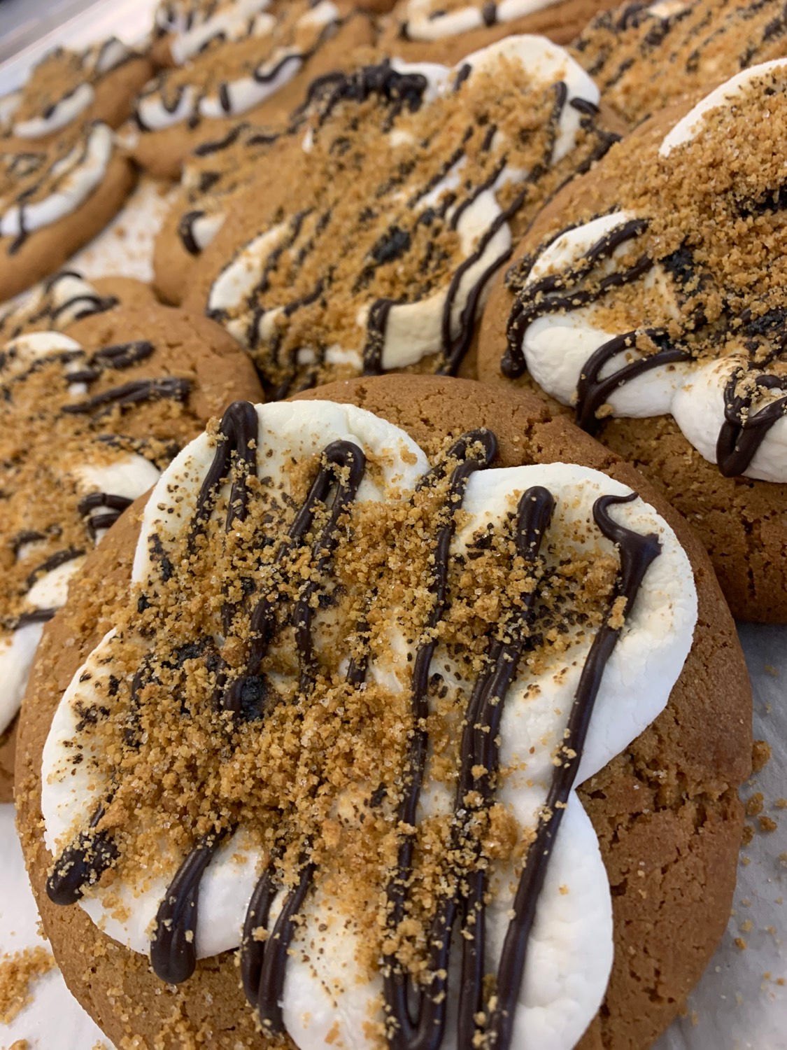 S’more Love cookies topped with toasted marshmallows, dark chocolate drizzle, and graham cracker crumbs.