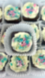 Rows of XOXO Brownies with vanilla buttercream frosting and Valentine’s Day themed sprinkles, presented in cupcake liners.