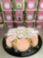 On The Rocks Cookie Assortment: Individually wrapped cookies with pink drizzle, presented on a black tray.