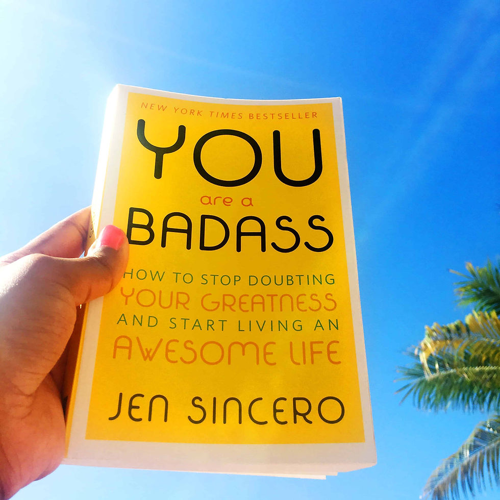 Yellow cover copy of You are a Badass by Jen Sincero against the background of a blue sky