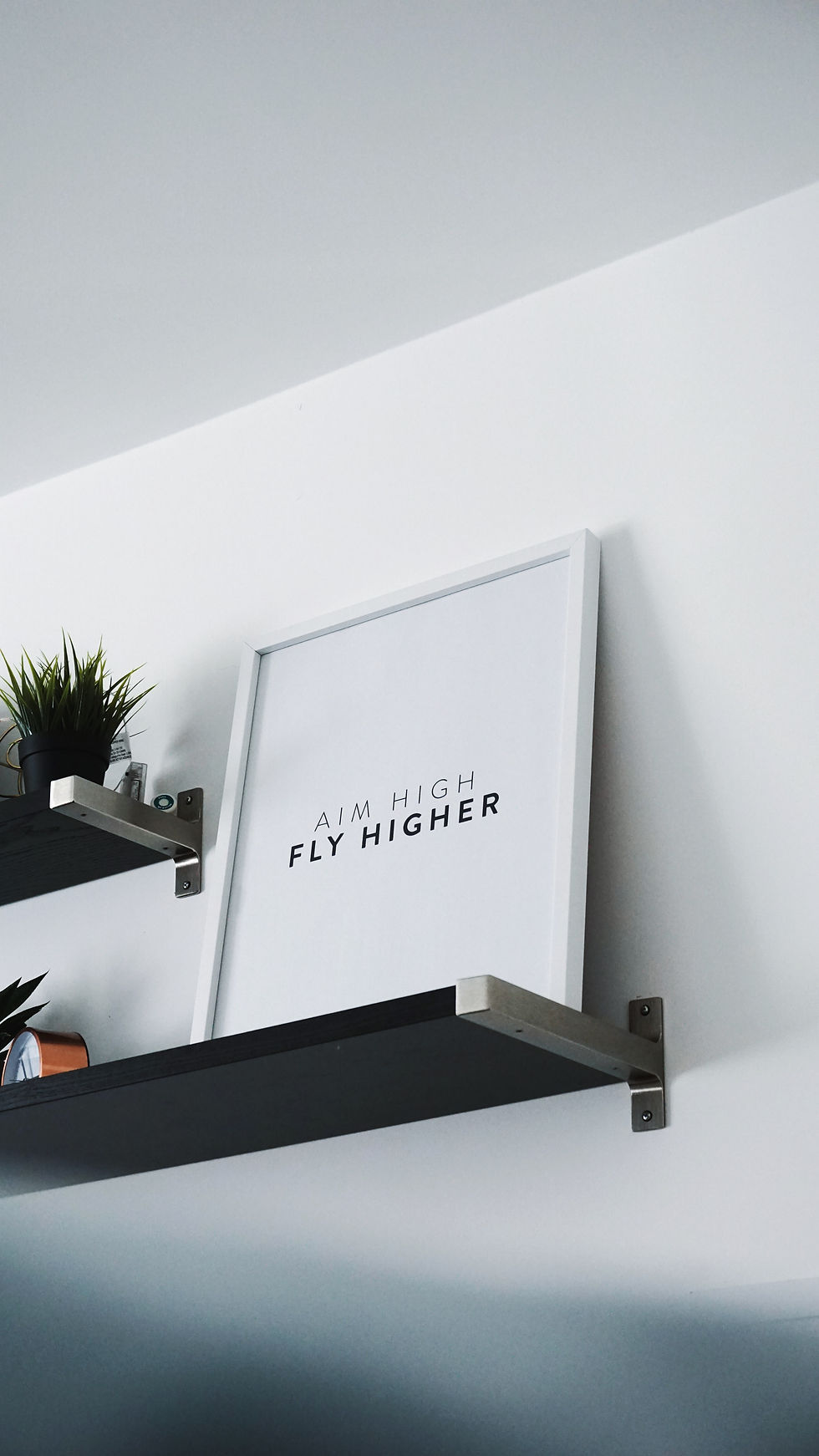 A framed quote sits on a shelf saying "Aim High, Fly Higher"