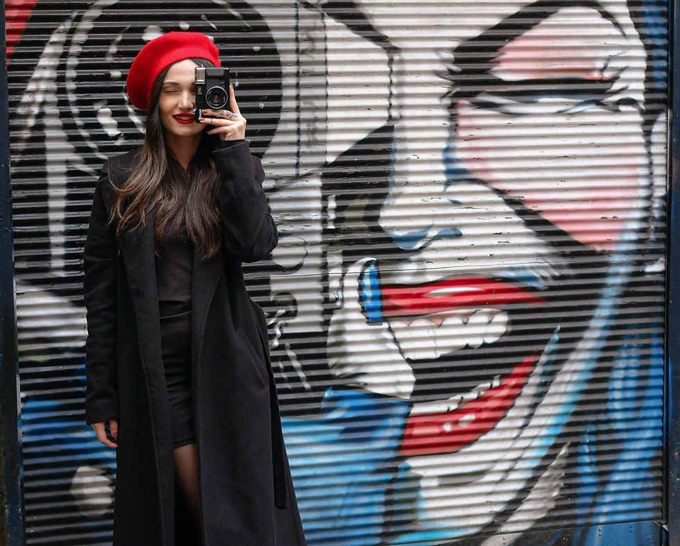 An image of a girl in a red beret posing with expressive wall art, representing how Gen Z seems to be attracted to maximalism.
