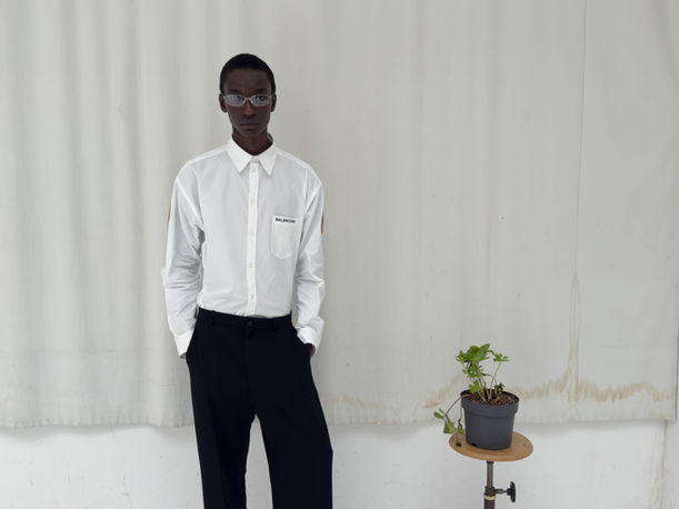 Studio portrait of ABD, male talent from Paris model agency, wearing Balenciaga white shirt with glasses in clean minimalist composition.