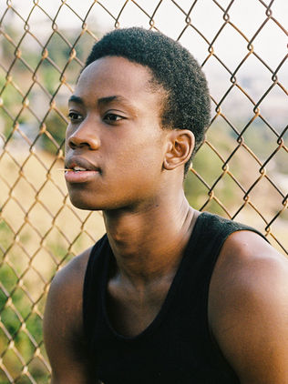 Young male model in tank top looks away from camera.